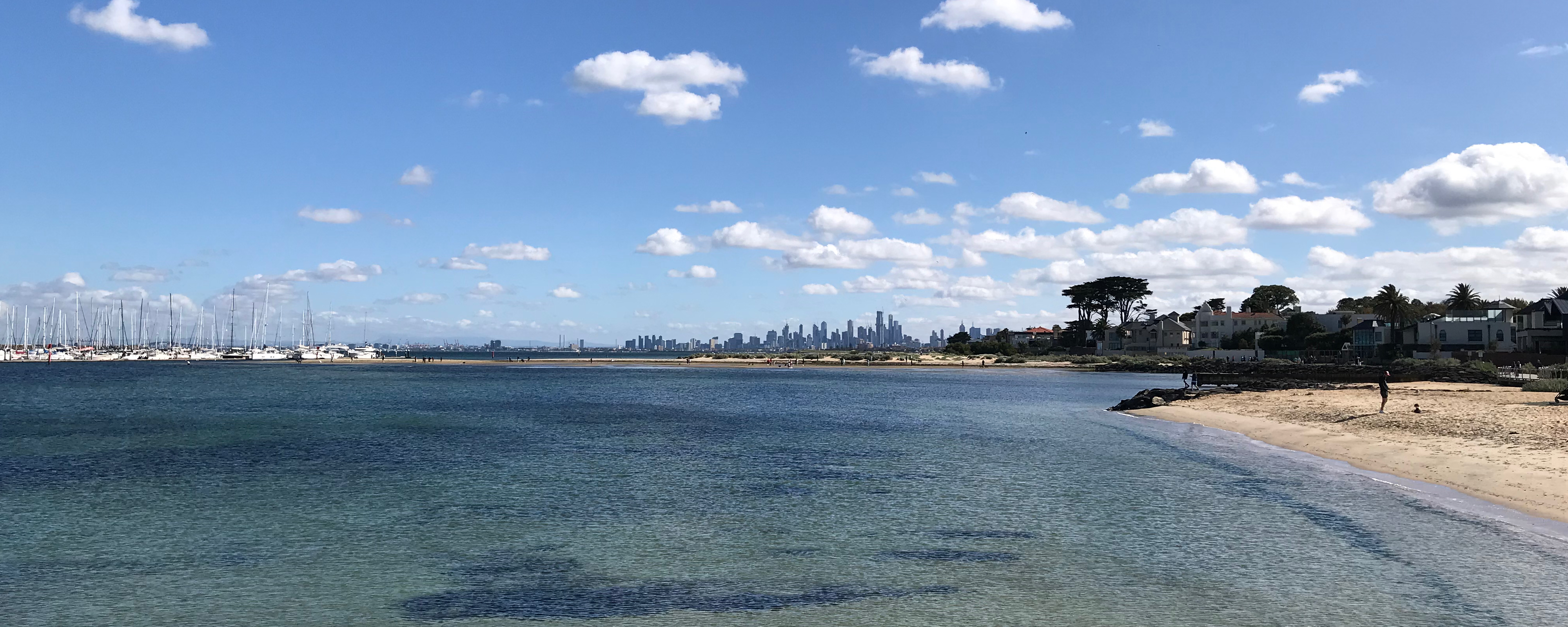 View of the skyscrapers in the CBD framed by the Middle Brighton Pier to the left and the beach on the right.